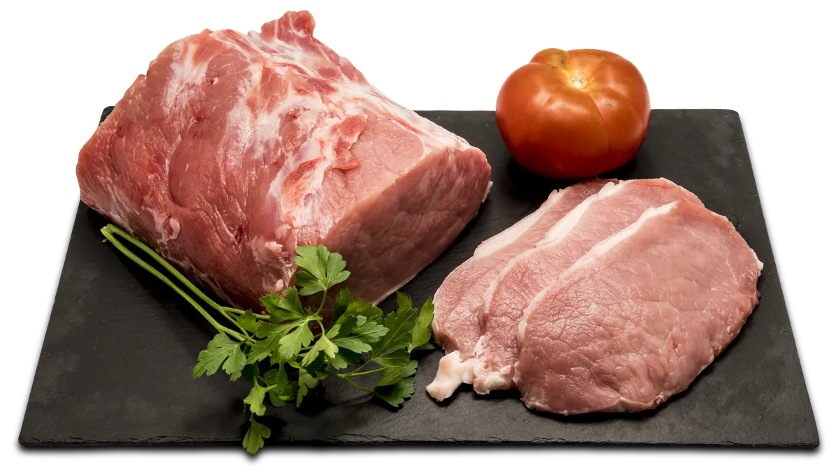 Cortes de carne presentados sobre una pizarra con tomate y perejil